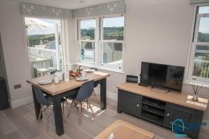 a living room with a table and a television at Beach View - Stylish Stay, Estuary Views & Luxury Spa Access in Salcombe