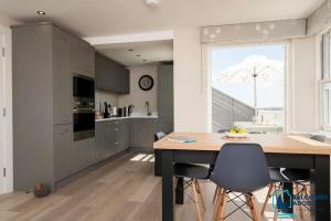 a kitchen with gray cabinets and a table with chairs at Beach View - Stylish Stay, Estuary Views & Luxury Spa Access in Salcombe