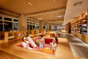 three girls sitting on a couch in a library at BEB5 Okinawa Seragaki by Hoshino Resorts in Onna