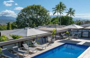 a pool with chairs and umbrellas on a resort at Monsoon Luxury Apartment in Port Douglas