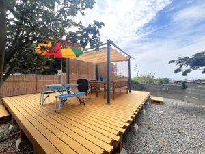 a wooden deck with a table and an umbrella at はたご屋ちゅうべ in Taki