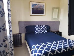 Schlafzimmer mit einem Bett mit einer blauen und weißen Bettdecke in der Unterkunft DB Tower Vacation Rental in Belize City