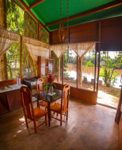 a dining room with a table and chairs and windows at Coco house tambopata in Puerto Maldonado