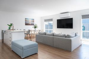 a white living room with a couch and a table at Sea Breeze Retreat in Cape Paterson