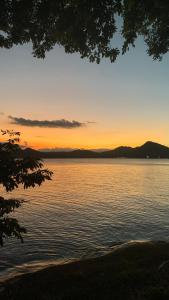 a sunset over a body of water with a tree at Hotel Las Brisas in Catemaco