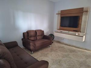 a living room with a couch and a chair and a television at Casa acolhedora para descanso in Brotas