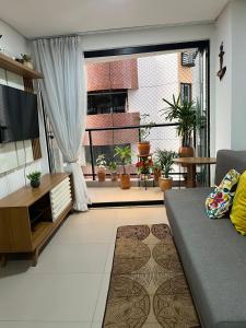 a living room with a couch and a large window at Praia do Cabo Branco- FLAT DO BZ- 2 quartos in Tambaú