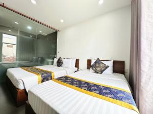 two beds in a hotel room with a window at K&T Hotel - Sân Bay Tân Sơn Nhất in Ho Chi Minh City