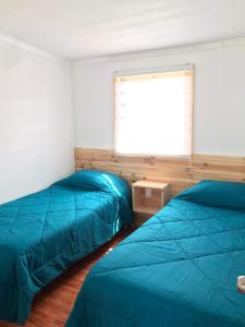 due letti in una stanza con finestra di Cabañas Aires de Huerquehue a Panguipulli Altre 3 foto