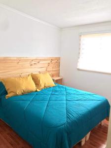 una camera da letto con un letto con un piumone blu e una finestra di Cabañas Aires de Huerquehue a Panguipulli