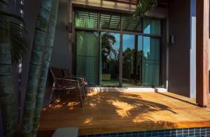 a patio with a chair and a large window at Вилла с бассейном на Най Харн, 3 спальни G7 in Rawai Beach +15 photos