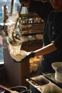 a woman is preparing a bowl of food in a kitchen at CLASSYC Hotel in Hanoi