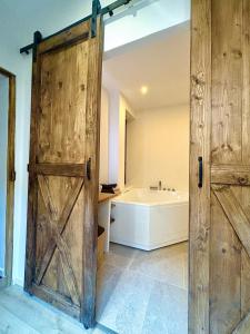 a bathroom with a wooden door and a bath tub at cinéma & balnéo privatif in Montfrin