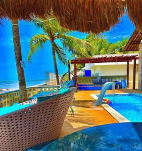 a resort with a swimming pool and palm trees at Pousada La Riviera - Pé na areia e Passeios em Maragogi in Maragogi