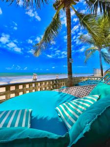 a row of blue pillows on a beach with palm trees at Pousada La Riviera - Pé na areia e Passeios em Maragogi in Maragogi