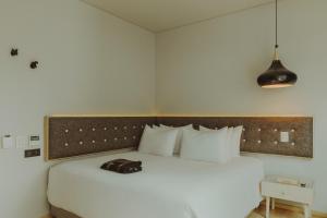 a bedroom with a large white bed with a purse on it at The Click Clack Hotel Bogotá in Bogotá