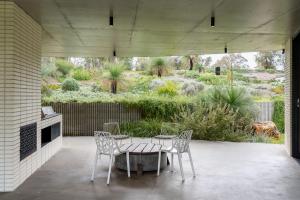a patio with a table and chairs and a garden at Boomerang House I Private Properties in Quindalup