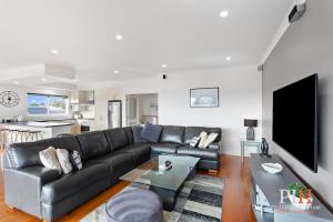 a living room with a black leather couch and a table at Spacious 4-Bd in Cowes sleeps 8 in Cowes