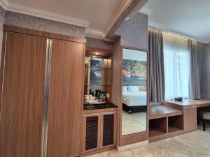a room with a bedroom with a desk and a mirror at GIIA Maluku Hotel Thamrin Jakarta in Jakarta