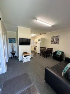 Una sala de estar con un sofá, un televisor y una mesa. en The Silver Bream Motel & Self Contained Units, en Mallacoota