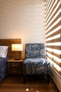 a bedroom with a chair and a bed and a lamp at Hotel San Benito Cuenca in Cuenca