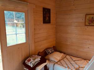 a room with a bed in a wooden room with a window at Aasa Summer Cottage in Surepi