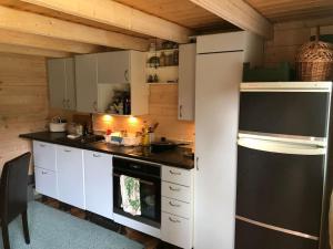 a kitchen with white cabinets and a black refrigerator at Aasa Summer Cottage in Surepi