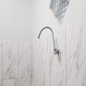 a bathroom with a shower with white marble tiles at Villa Cahaya 2 Guci Mitra RedDoorz in Tuwel +28 photos