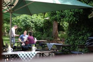 a group of people sitting at tables under an umbrella at Kreilingshöfchen Apartments in Bad Vilbel