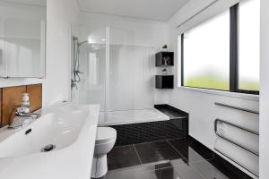 a white bathroom with a sink and a toilet at Sunrise Lookout - Paihia Holiday Home in Haruru +30 photos