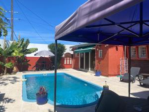 - une piscine avec un parasol bleu à côté d'une maison dans l'établissement Runloc974 Appart, à Saint-Louis