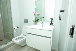 a white bathroom with a toilet and a sink at Ellipse Executive Haven in Midrand
