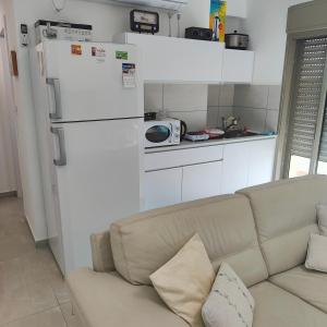 a living room with a couch and a white refrigerator at הבית קרוב לחוף in Ashkelon