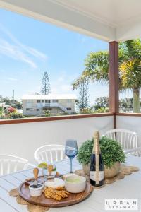 a table with a plate of food and a bottle of wine at Bargara Coastal Luxe Aircon, Outside Pet, Sleeps 8 in Bargara