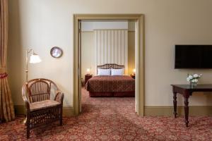 a bedroom with a bed and a chair and a mirror at Hadley's Orient Hotel in Hobart