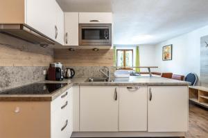 a kitchen with white cabinets and a microwave at Apartment Anton Huter in Sankt Anton am Arlberg