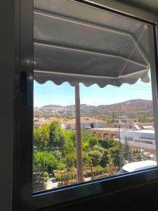 a window with a view of a city at Cozy apartment near to the airport in Kouvarás