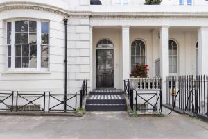 a white house with a black door and stairs at Cosy Little Venice Pied-à-Terre by MoreThanStays in London