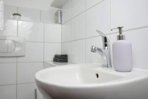 a white bathroom sink with a soap dispenser on it at Moderne 3-Zimmer-Wohnung für bis zu 7 Personen in Friesenheim +6 photos