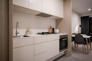 メルボルンにあるMt1012 - 1 BR Docklands Delight, Stunning Apartmentの白いキャビネットとシンクとテーブルのあるキッチン