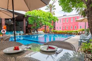 a swimming pool with chairs and a table and an umbrella at The Train Resort in Jomtien Beach