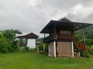 a house with a balcony on a grass field at บ้านนาสลี cottage บ่อเกลือ in Ban Pha Khap