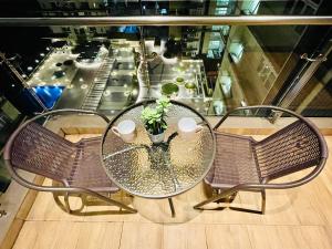 a glass table with two chairs and a table with a plant at Kuching City Center Riverine Apartment With Balcony and Garden View in Kuching