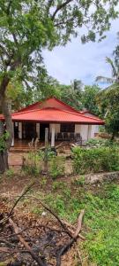 a small building with a red roof and a porch at Yala Reach Hotel in Tissamaharama