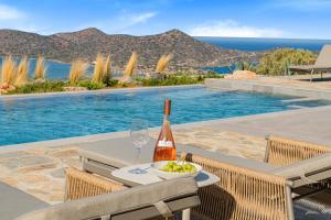eine Flasche Wein und eine Schale mit Trauben auf einem Tisch am Pool in der Unterkunft Sole Mare Luxury Villa With Sea View & Private Pool in Elounda in Elounda