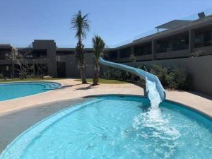 a swimming pool with a water slide in a building at Luxury Apartment in Pebble Beach Umhlanga in Umhlanga