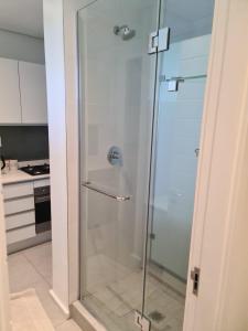 a shower with a glass door in a kitchen at Pebble Beach Resort Apartment in Umhlanga