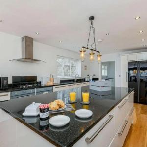 a kitchen with a black counter top with two glasses of orange juice at Cysgod Y Dyffryn - Luxury holiday cottage sleeping 8, Hot Tub available in Pen-y-groes