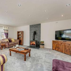 a living room with a couch and a fireplace at Cysgod Y Dyffryn - Luxury holiday cottage sleeping 8, Hot Tub available in Pen-y-groes