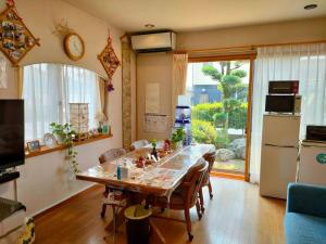 a kitchen with a table with chairs and a refrigerator at 民泊マエダハウス B&B Maeda House in Aira